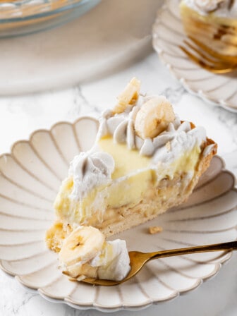 Slice of banana cream pie on plate with tip on fork