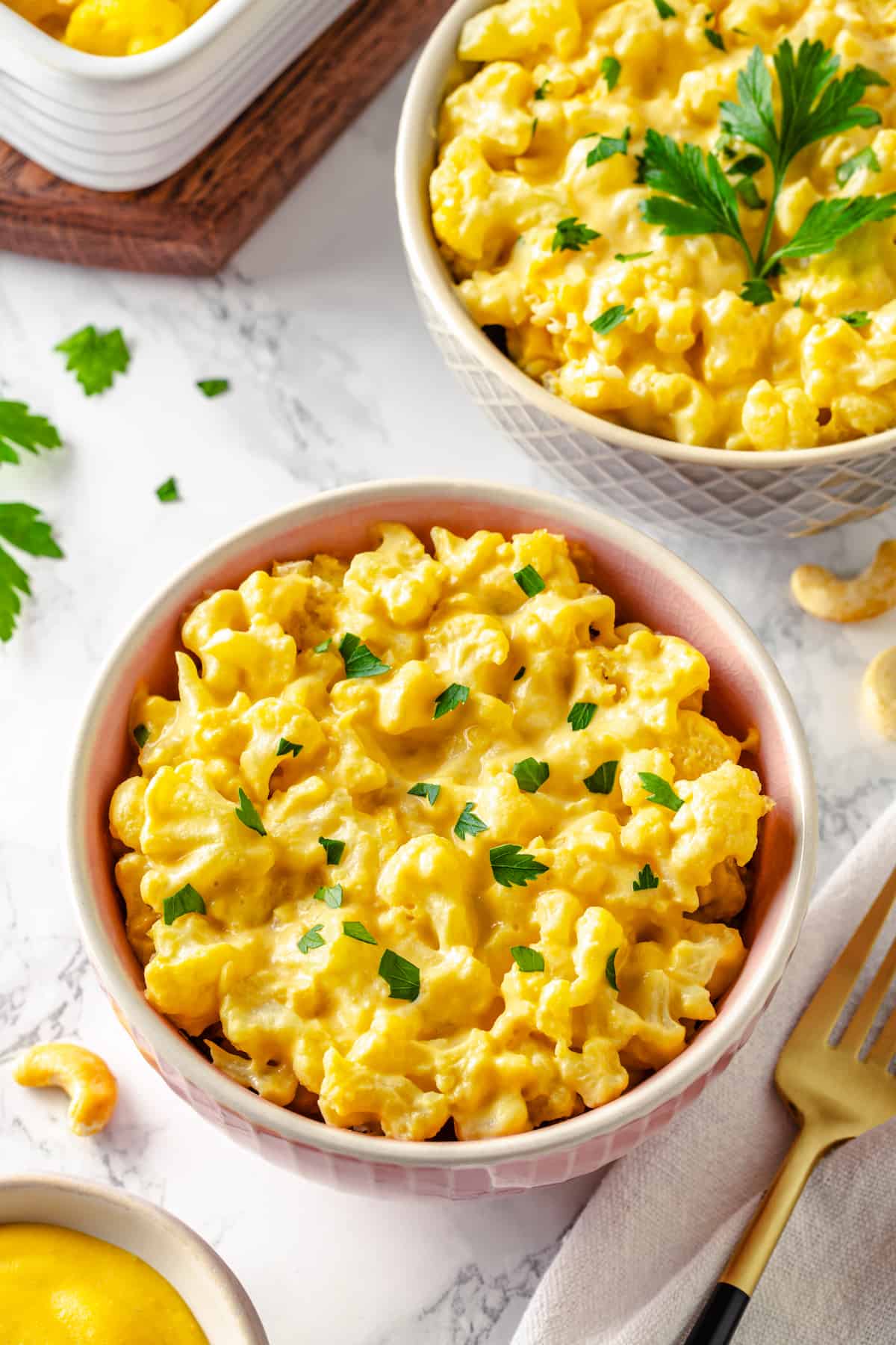 Two bowls over cauliflower mac and cheese topped with parsley