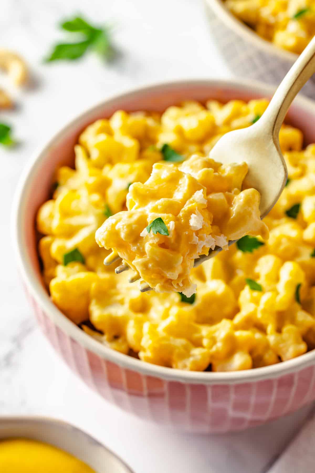 Fork of cauliflower mac and cheese held over bowl