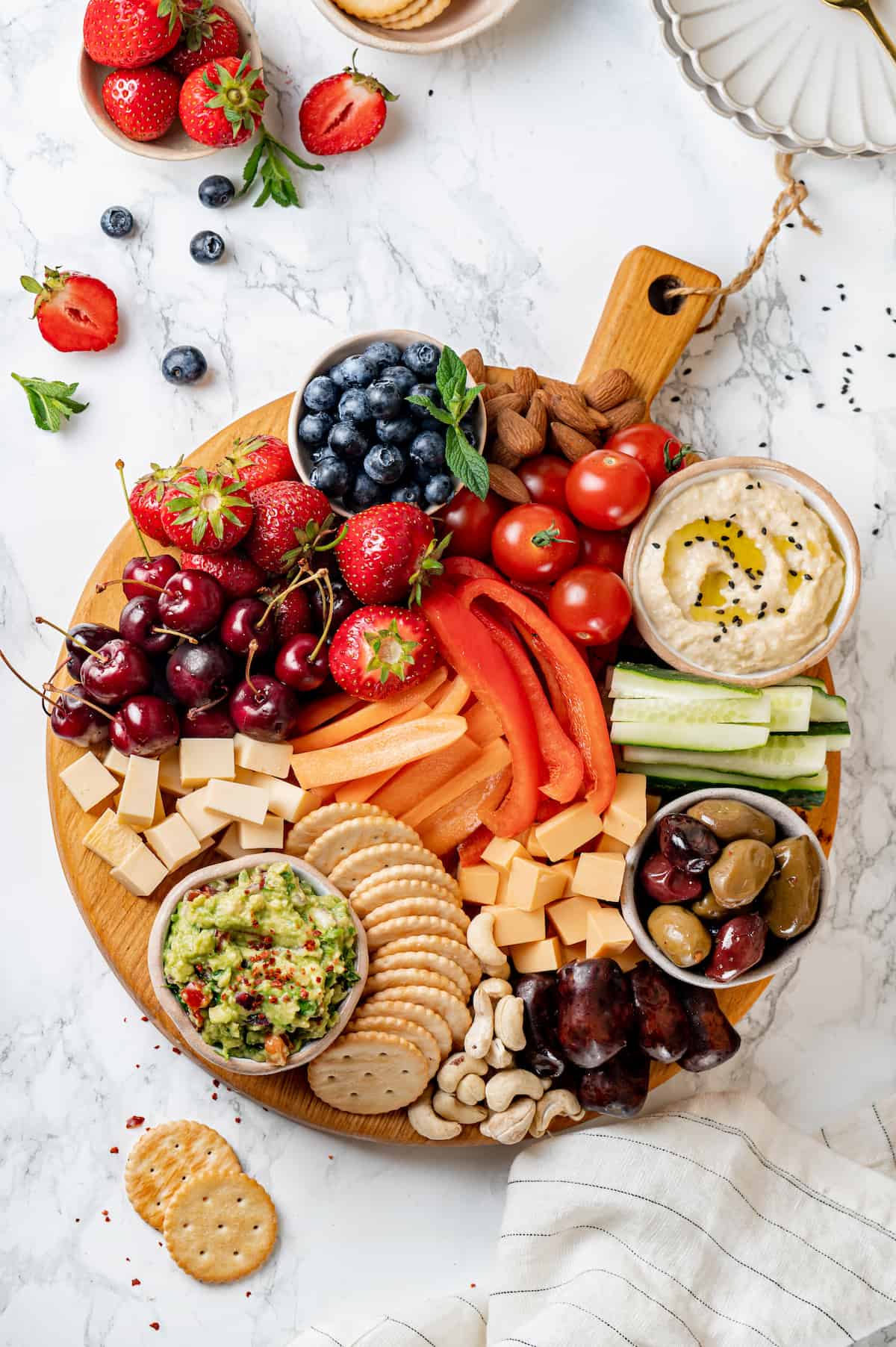 Overhead view of Vegan charcuterie board with cheese, olives, nuts, fruits, and veggies