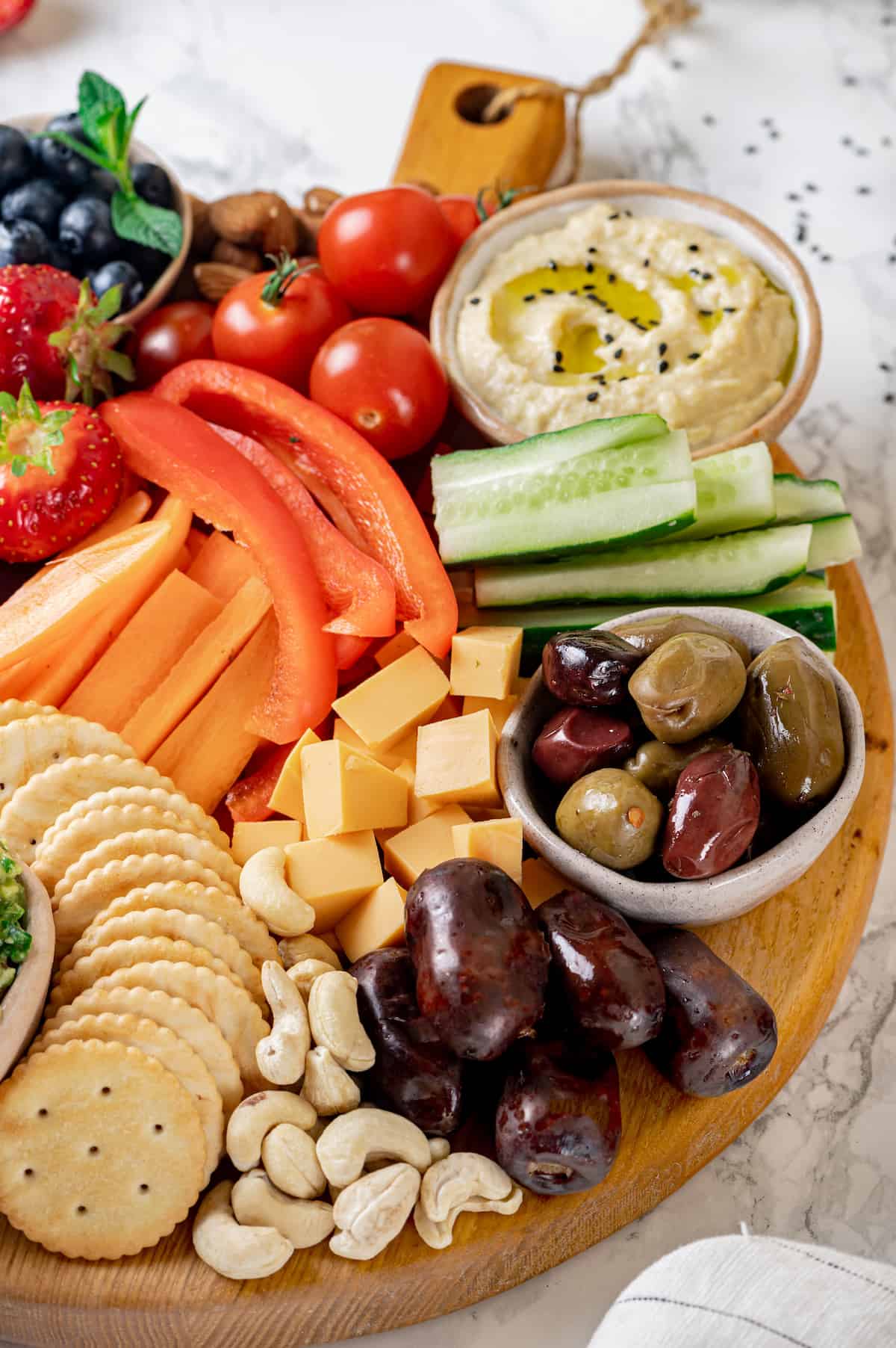Vegan charcuterie board with cheese, olives, nuts, fruits, hummus, and veggies