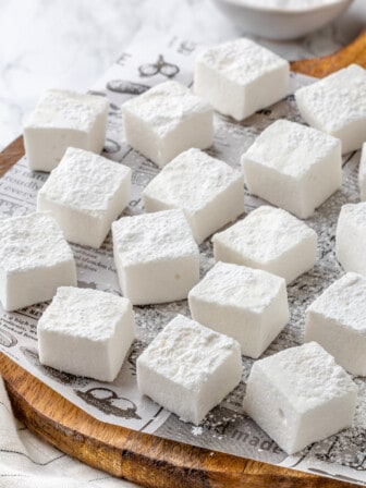 Vegan marshmallows arranged on newspaper-lined cutting board