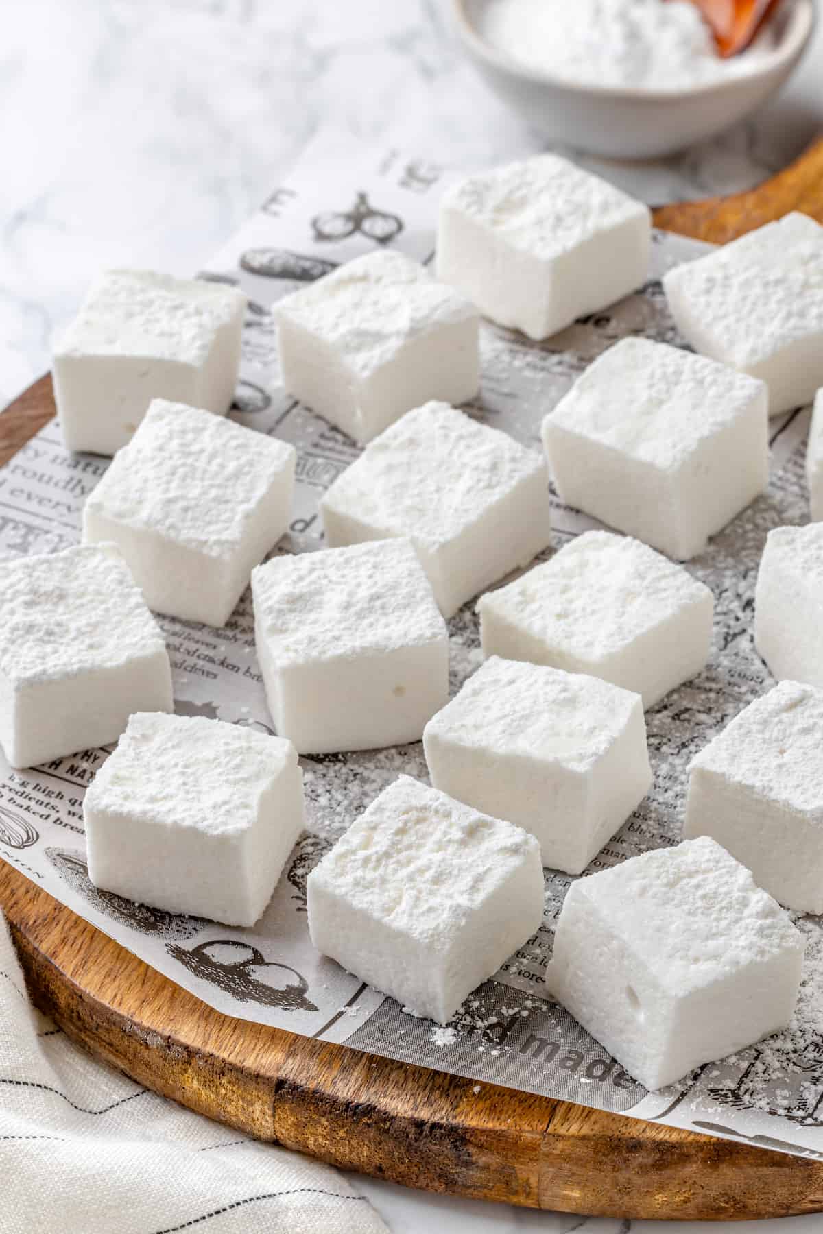 Vegan marshmallows arranged on newspaper-lined cutting board