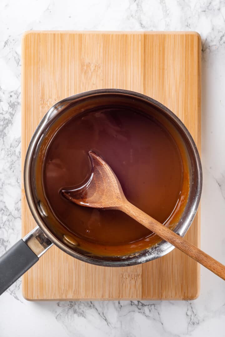 Overhead view of caramel sauce in pan with wooden spoon