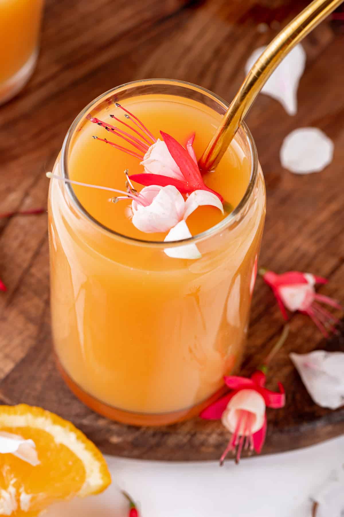 Glass of POG juice with gold straw and flower garnish