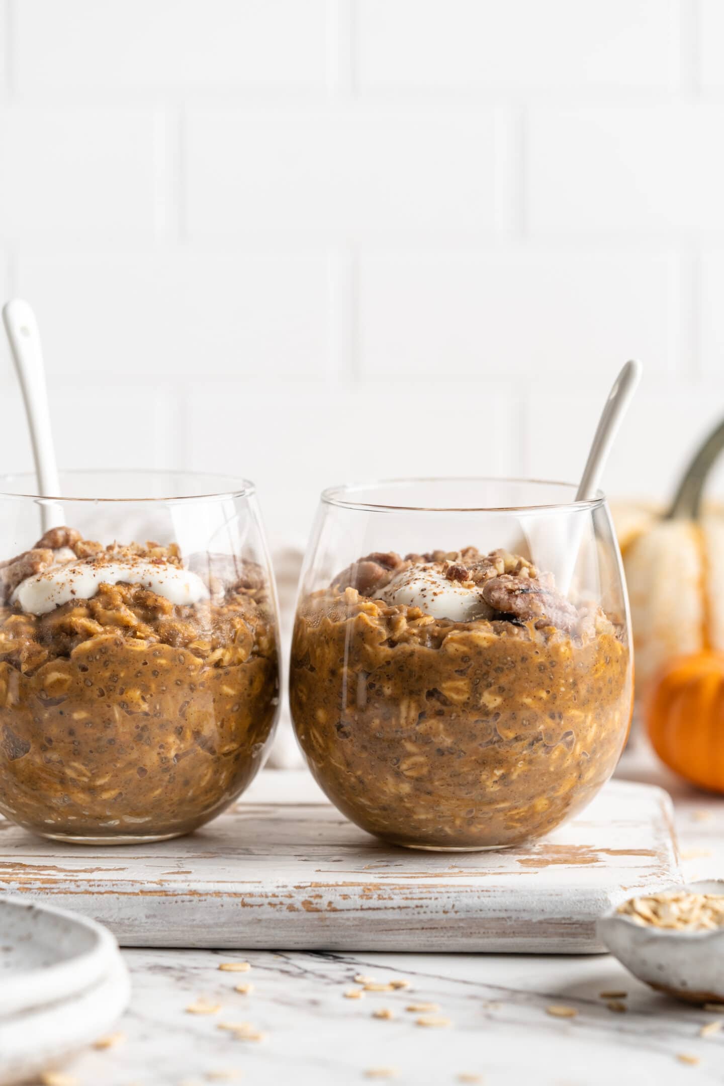 two jars of pumpkin pie overnight oats with spoons inside head on shot