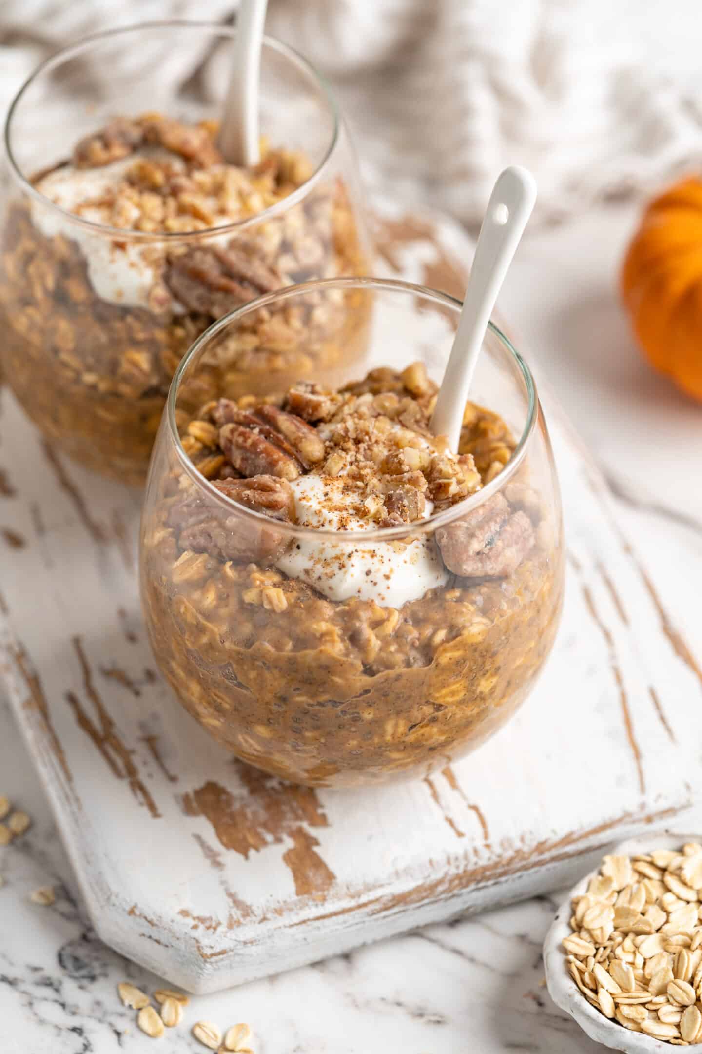 two jars of pumpkin pie overnight oats with spoons inside 45 degree angle shot