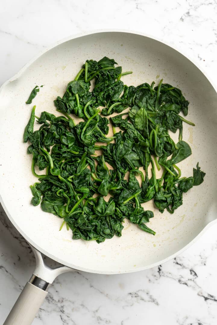 Overhead view of wilted spinach in skillet