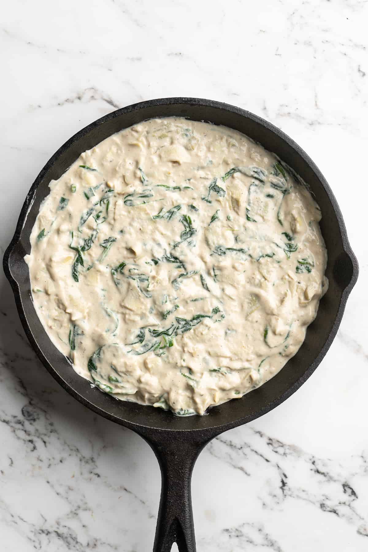 Overhead view of spinach artichoke dip in cast iron skillet
