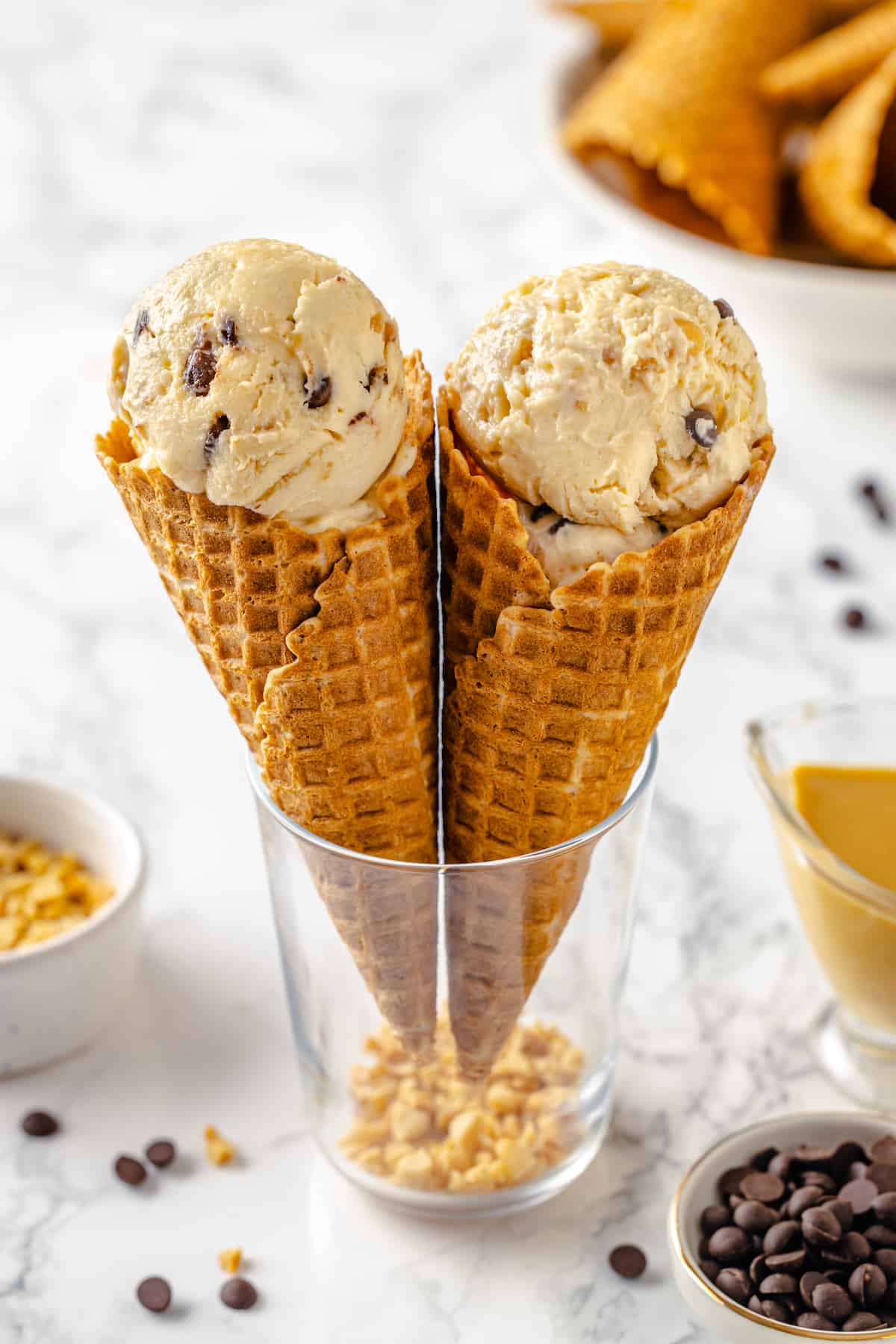 Two waffle comes filled with peanut butter ice cream standing in glass