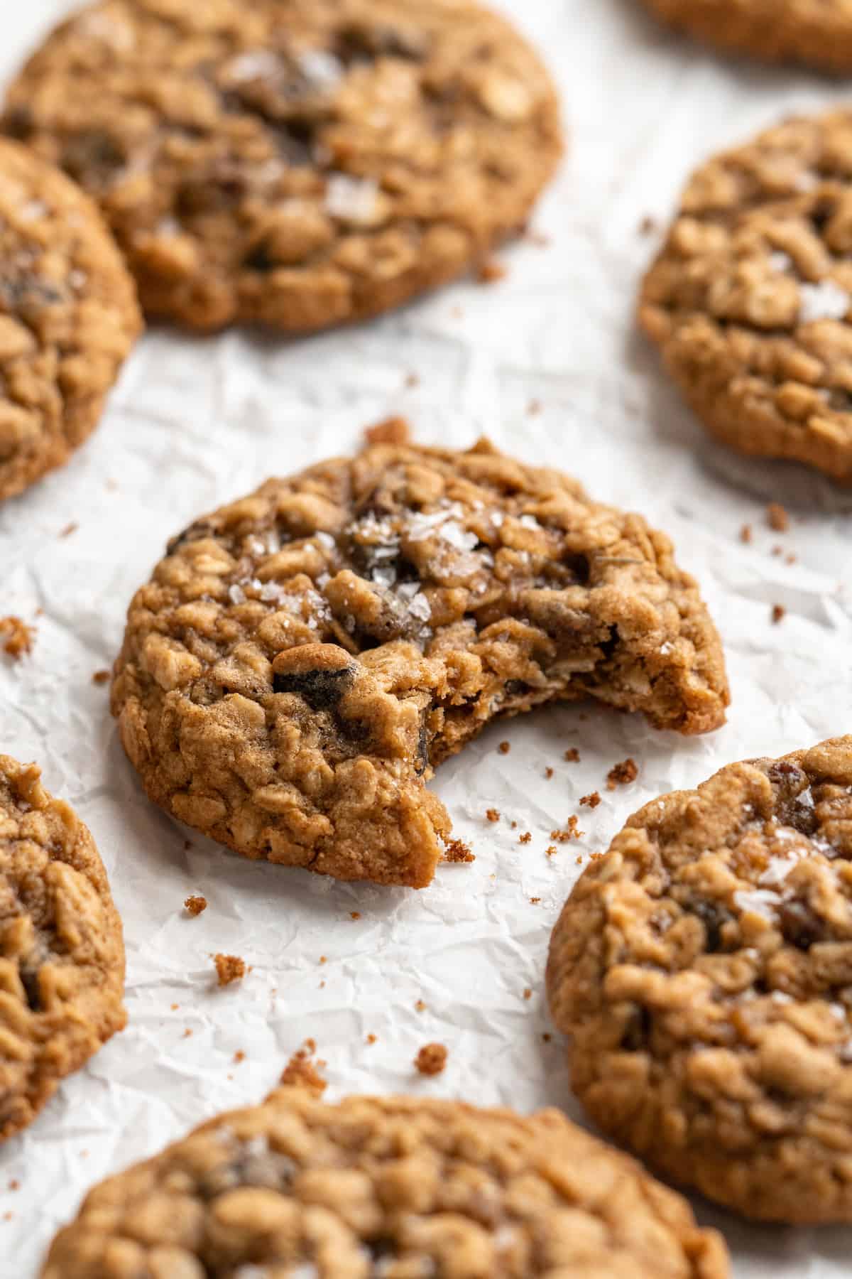 Vegan oatmeal cookies on parchment paper with center cookie bitten into