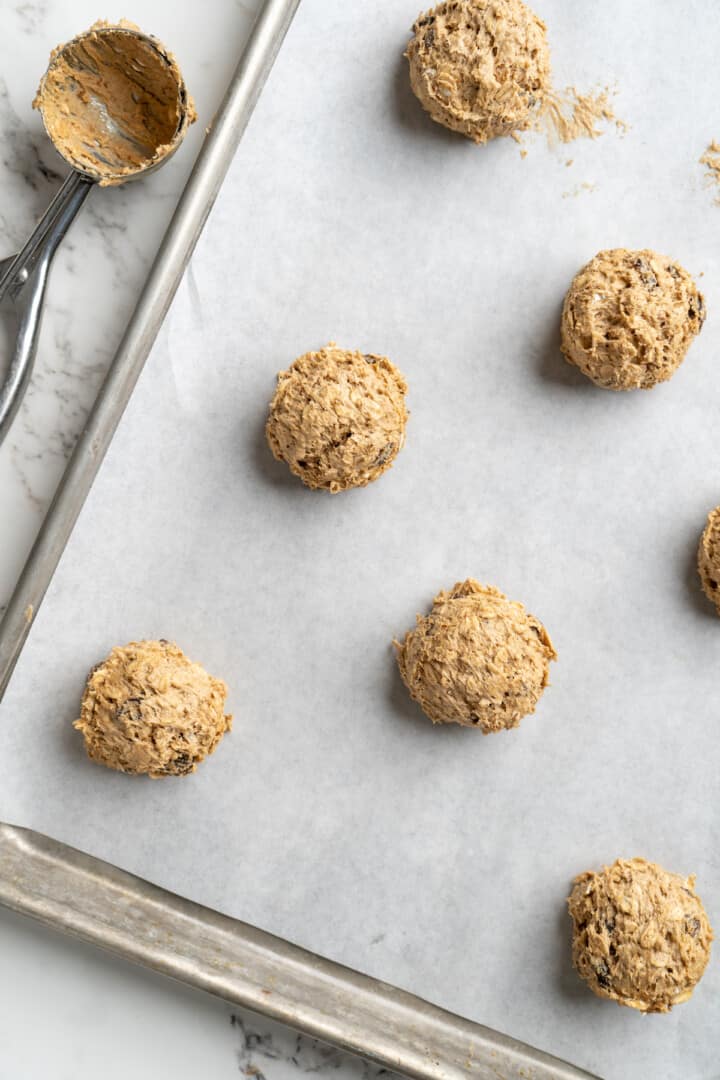 Overhead view of oatmeal cookie dough balls on parchment-lined baking sheet