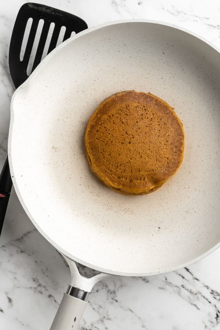 Overhead view of a cooked pumpkin pancake in a pan.