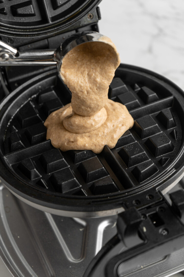 Waffle batter being scooped into a waffle iron