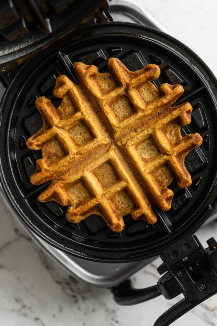 A pumpkin waffle in a waffle iron