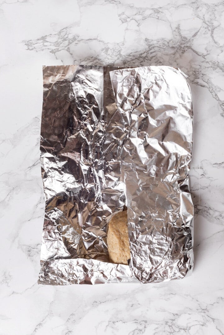 Overhead view showing how to wrap seitan chicken in foil