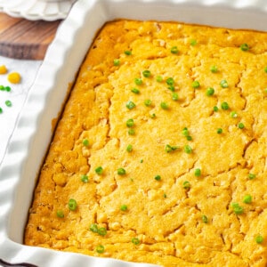 Cornbread pudding in white casserole dish with green onions scattered over top