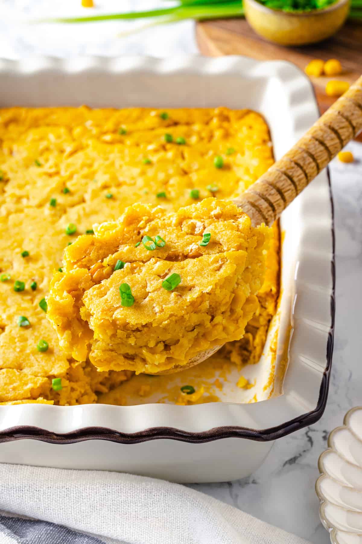 Vegan cornbread pudding being scooped from casserole dish
