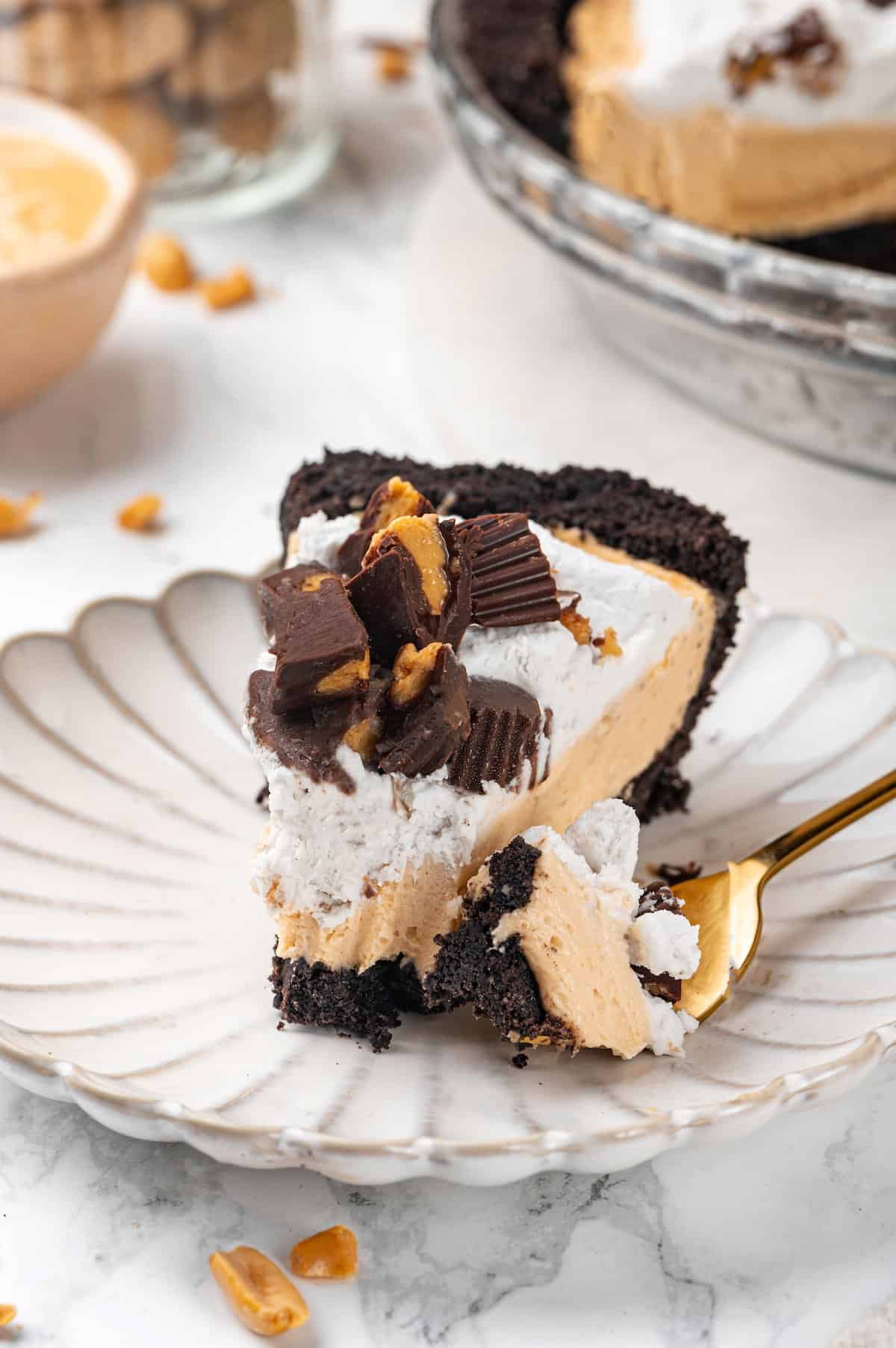 Slice of no-bake peanut butter pie on plate with tip of pie on fork