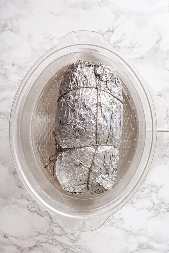 Overhead view of vegan turkey wrapped in foil for steaming