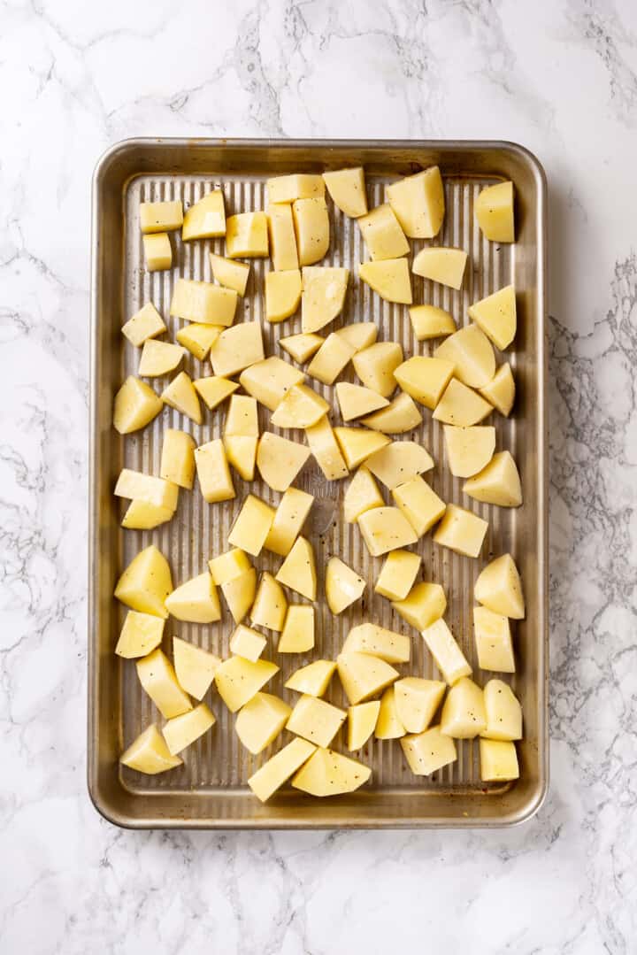 Overhead view of uncooked potatoes on baking sheet