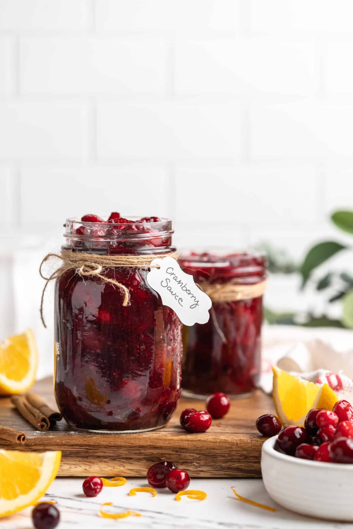 Two jars of cranberry orange sauce on cutting board