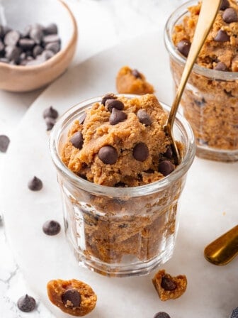 Jar of protein cookie dough with spoon, with another jar of dough in background