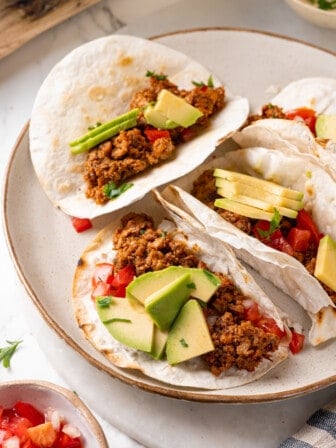 Soyrizo tacos on plate with avocado and diced tomatoes