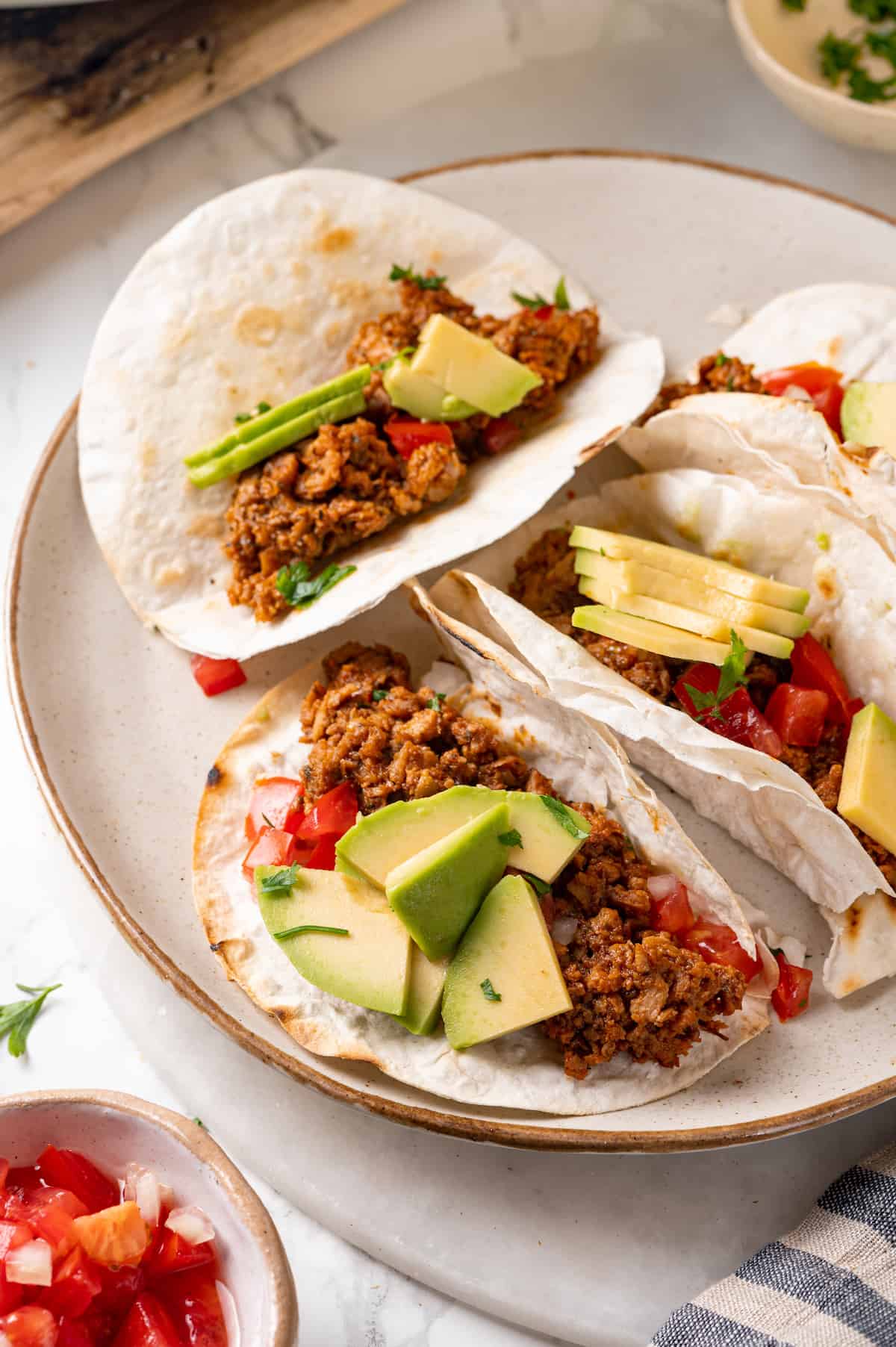 Soyrizo tacos on plate with avocado and diced tomatoes