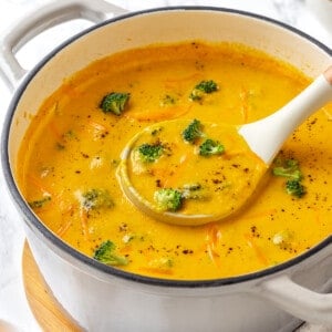Ladling serving of vegan broccoli cheddar soup from pot