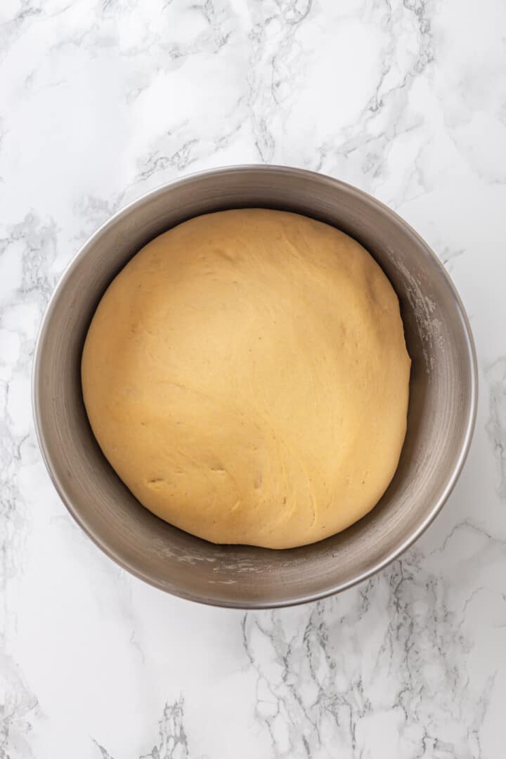 Overhead view of dough for cinnamon rolls in mixing bowl