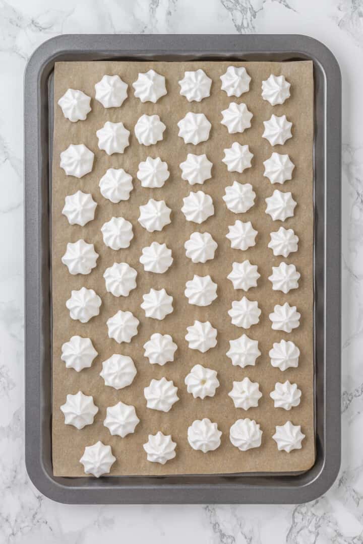 Overhead view of aquafaba meringues on parchment lined baking sheet