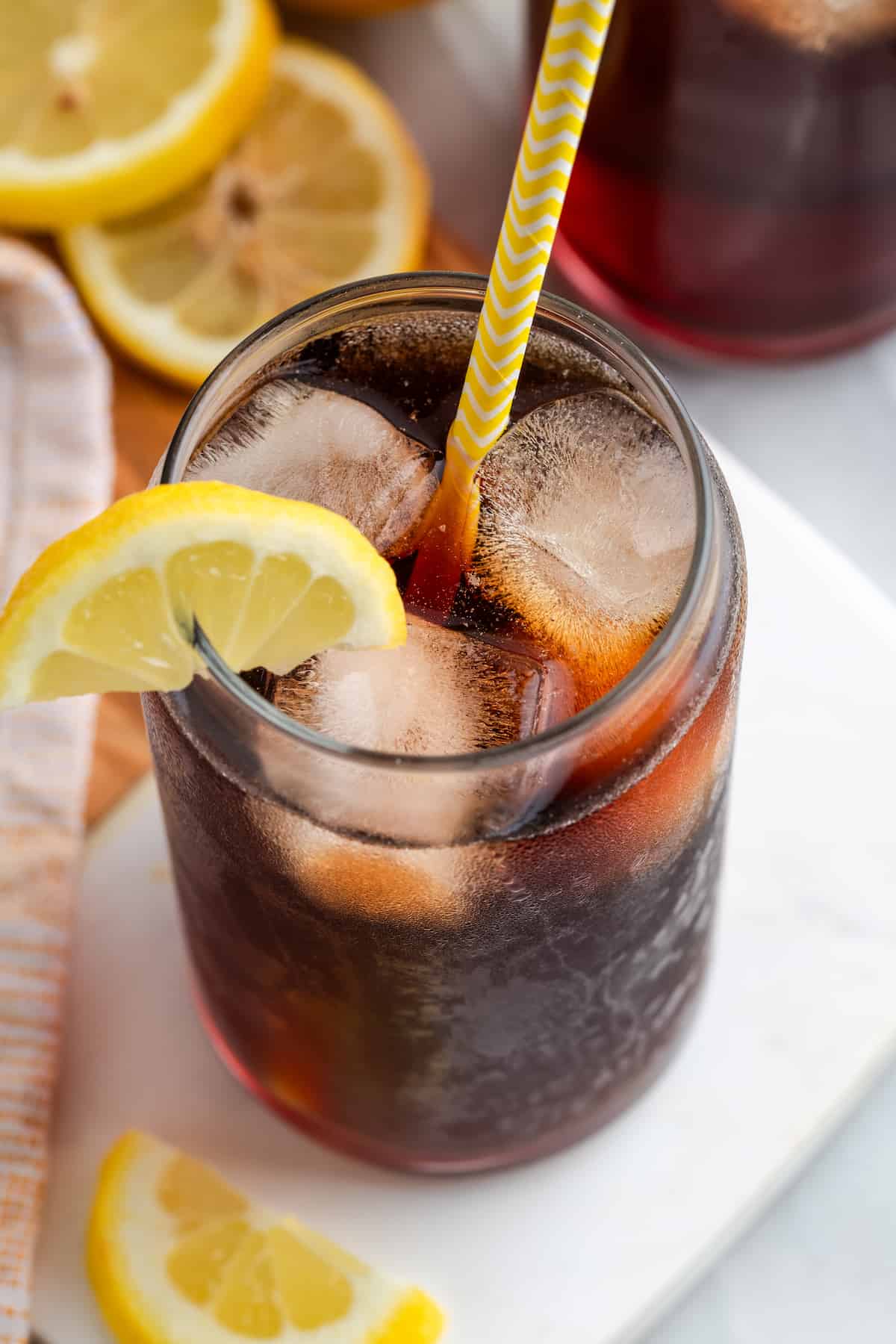 Top down view of Southern sweet tea in glass with ice and straw, with lemon wedge on rim