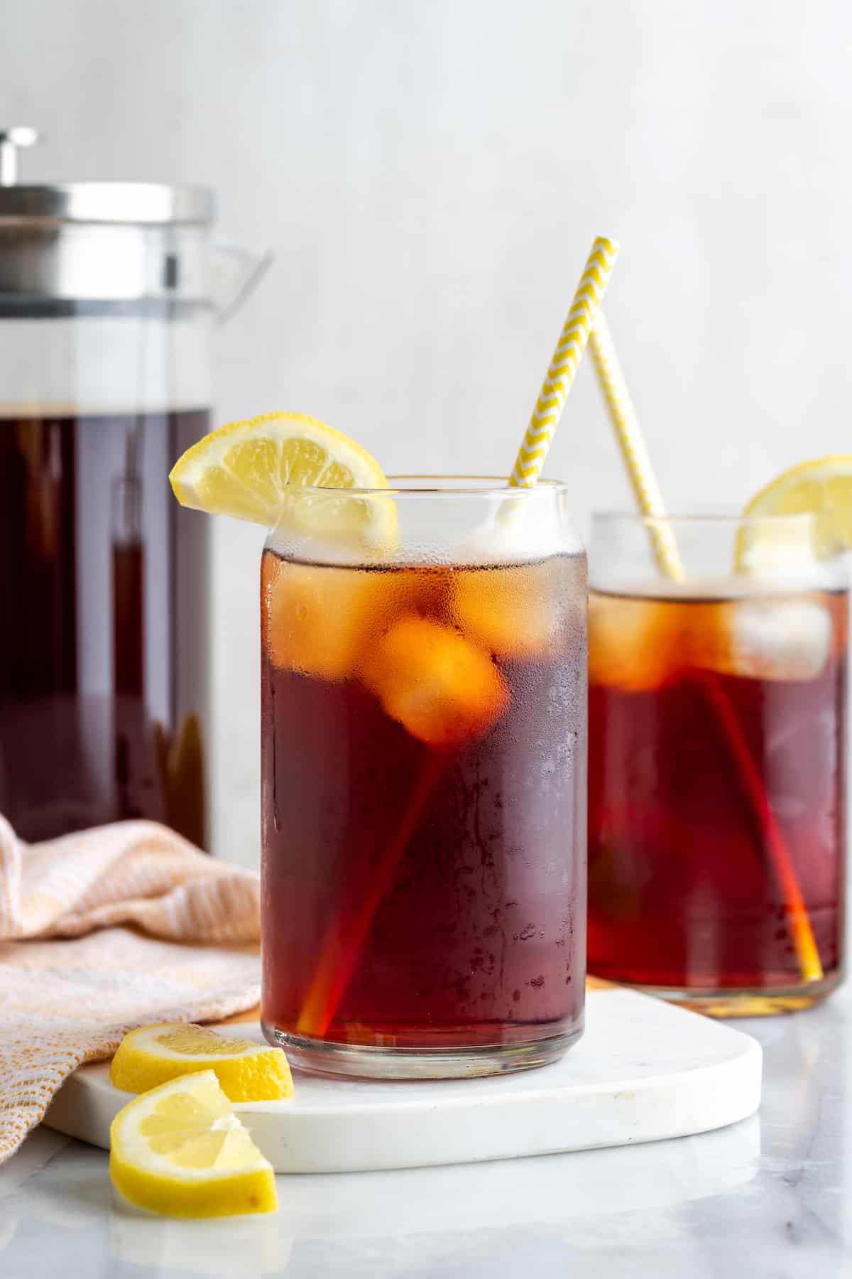 Two glasses of Southern sweet tea with yellow straws and lemon slices