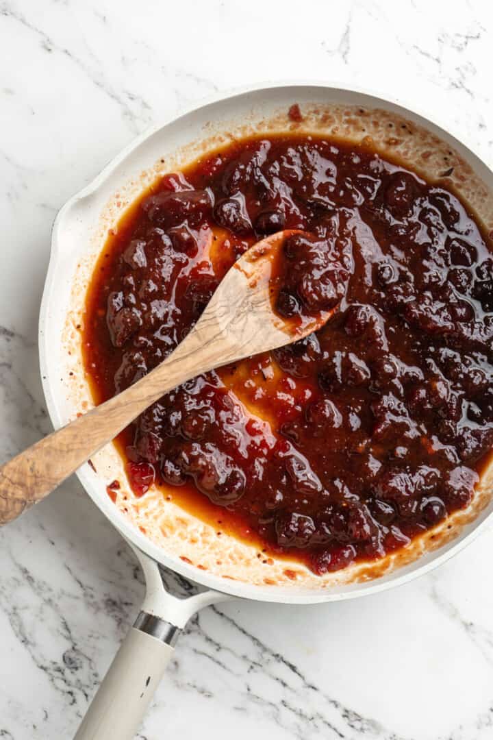 Overhead view of cranberry sauce in skillet with wooden spoon