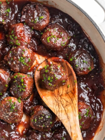 Overhead view of vegan cranberry meatballs in pan with wooden spoon