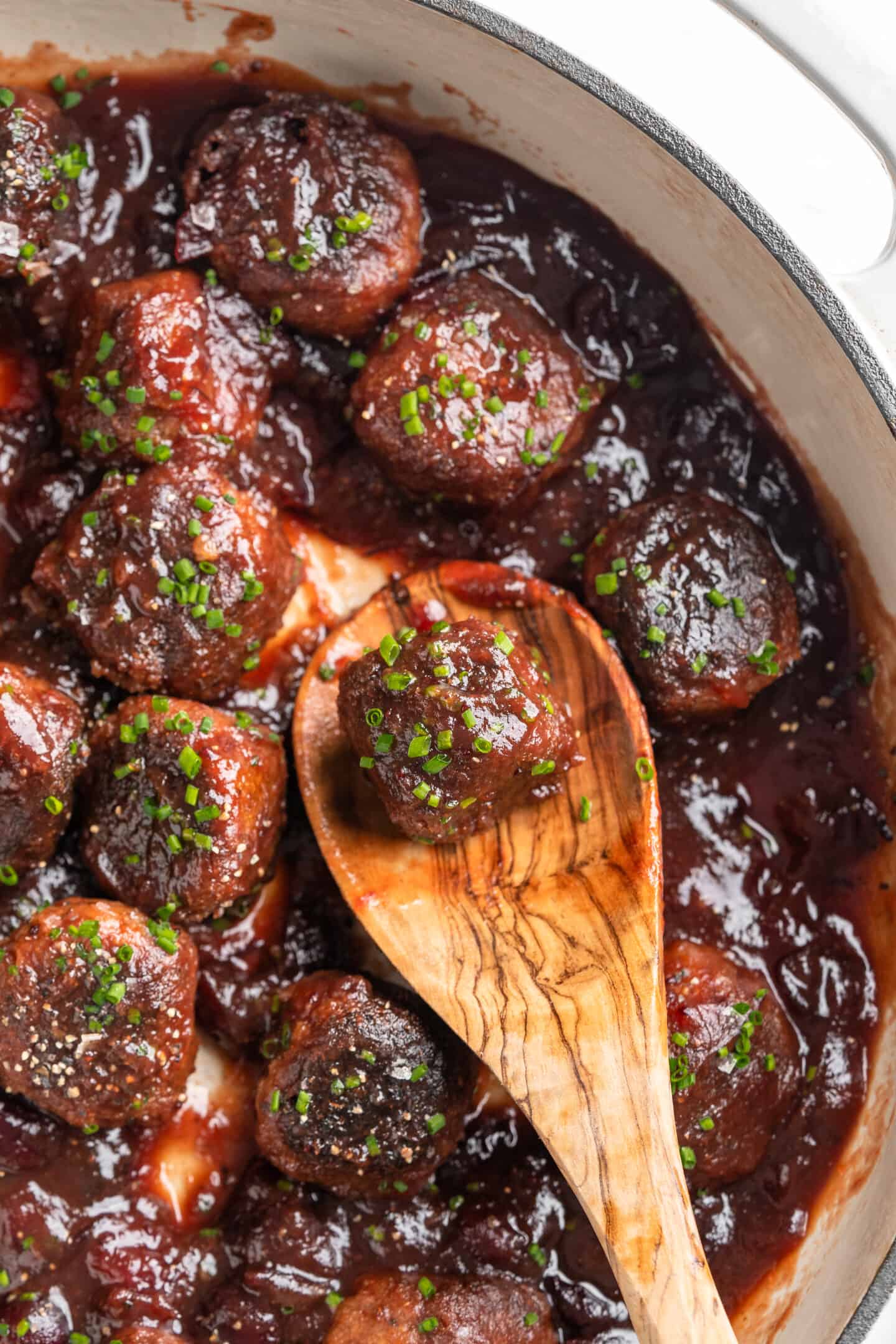 Overhead view of vegan cranberry meatballs in pan with wooden spoon