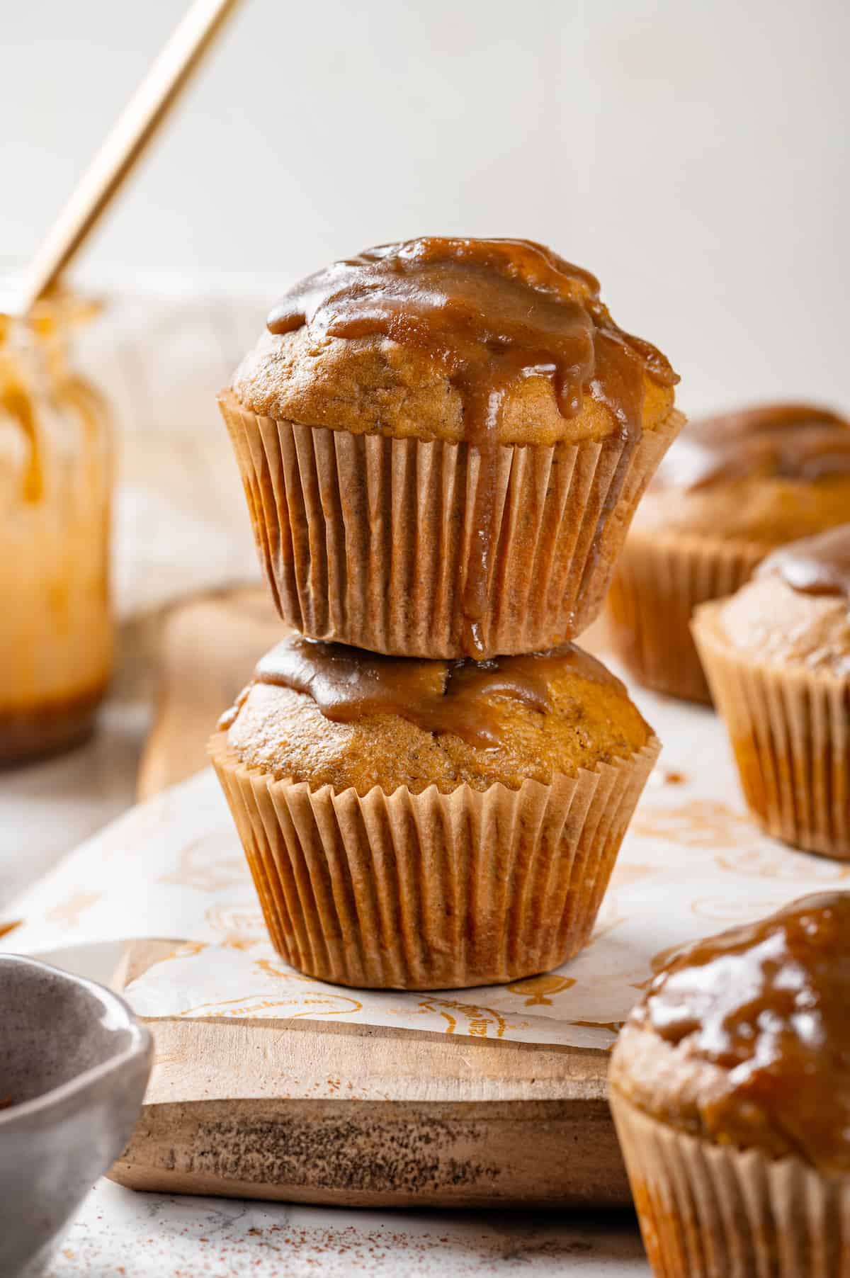 Two glazed pumpkin banana muffins stacked on board