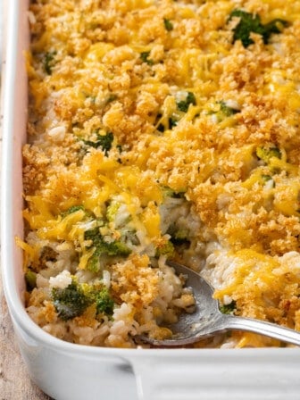 Casserole dish of broccoli cheese rice casserole with serving spoon