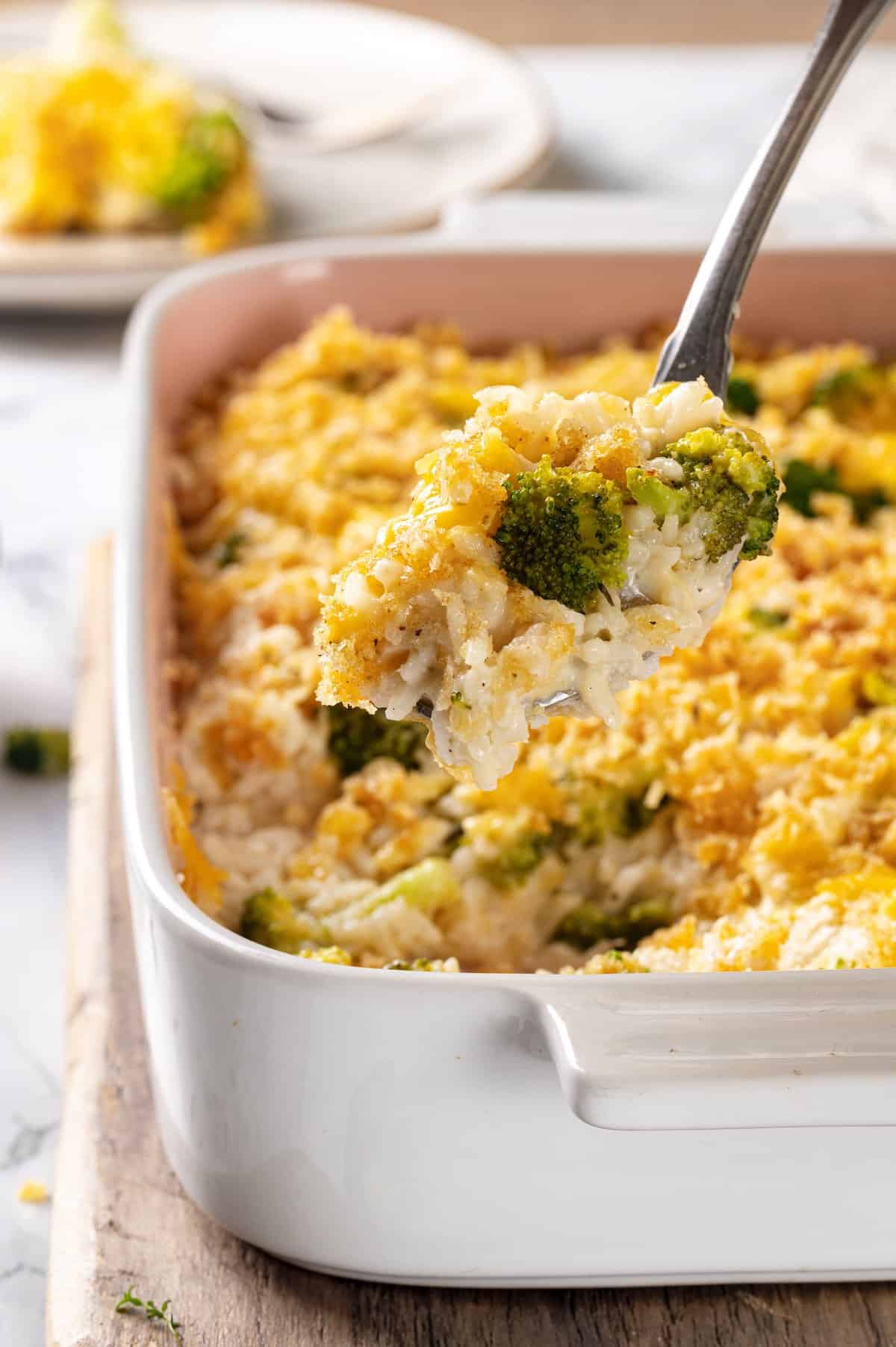 Serving spoon lifting portion of broccoli cheese rice casserole from dish