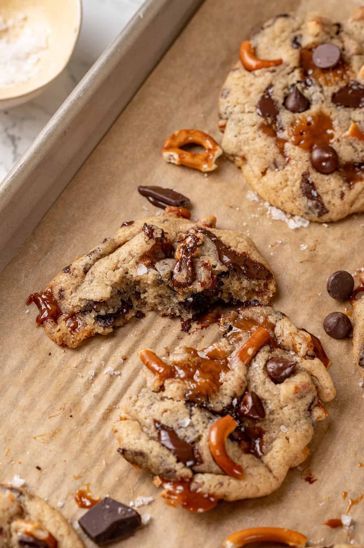 Kitchen sink cookies on parchment-lined baking sheet with one cookie broke in half