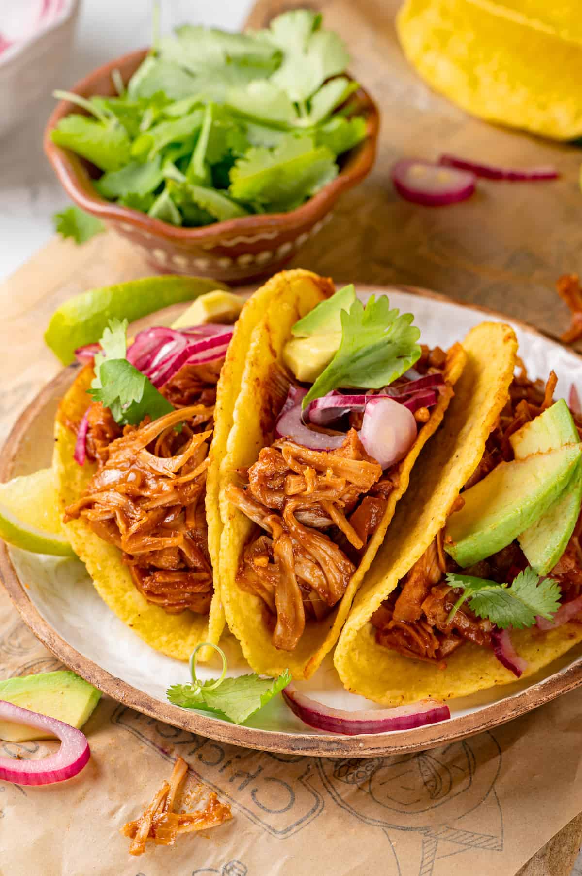 3 jackfruit tacos on plate with pickled onions, cilantro, and avocado