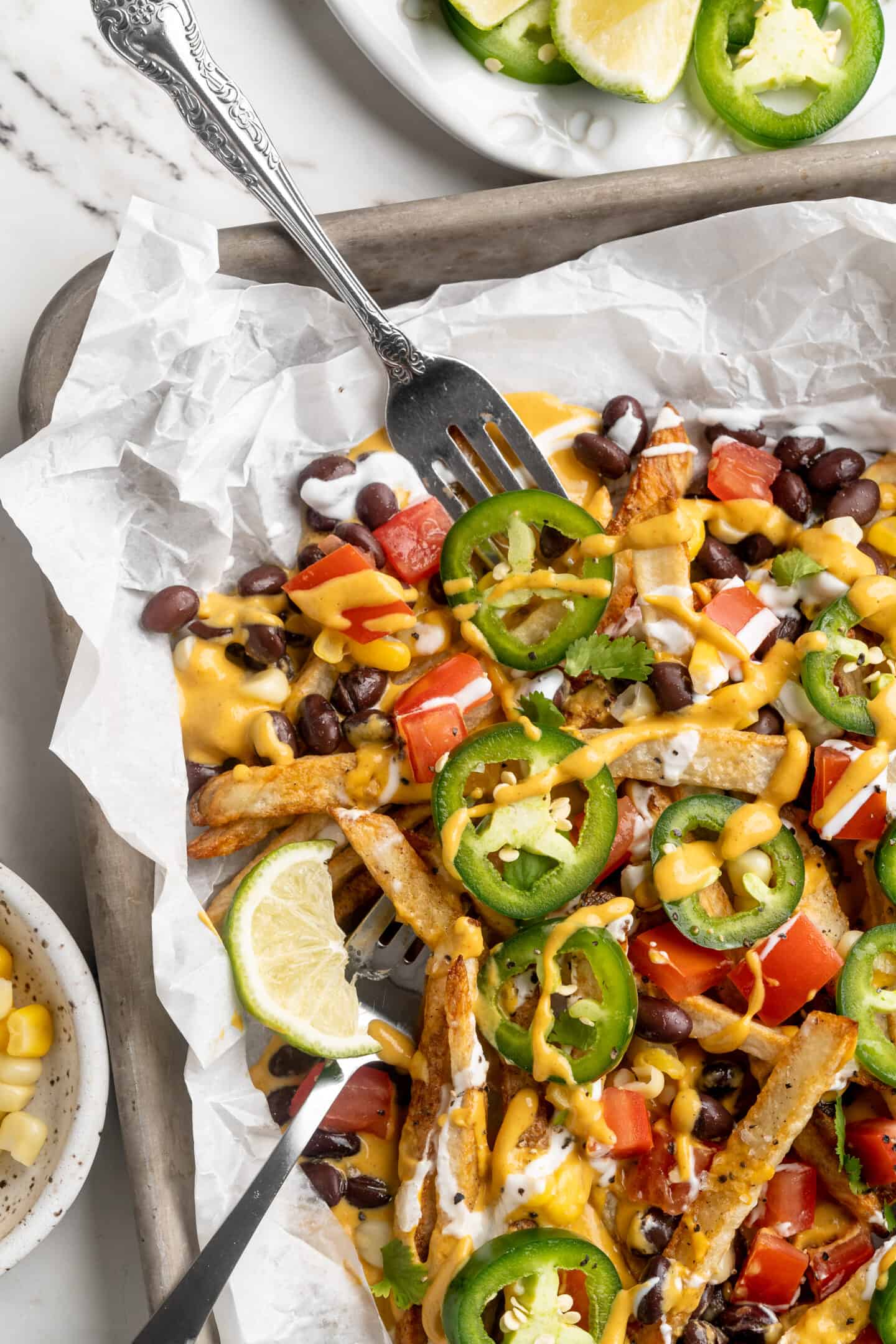 Sheet pan with loaded nacho fries, with forks digging in