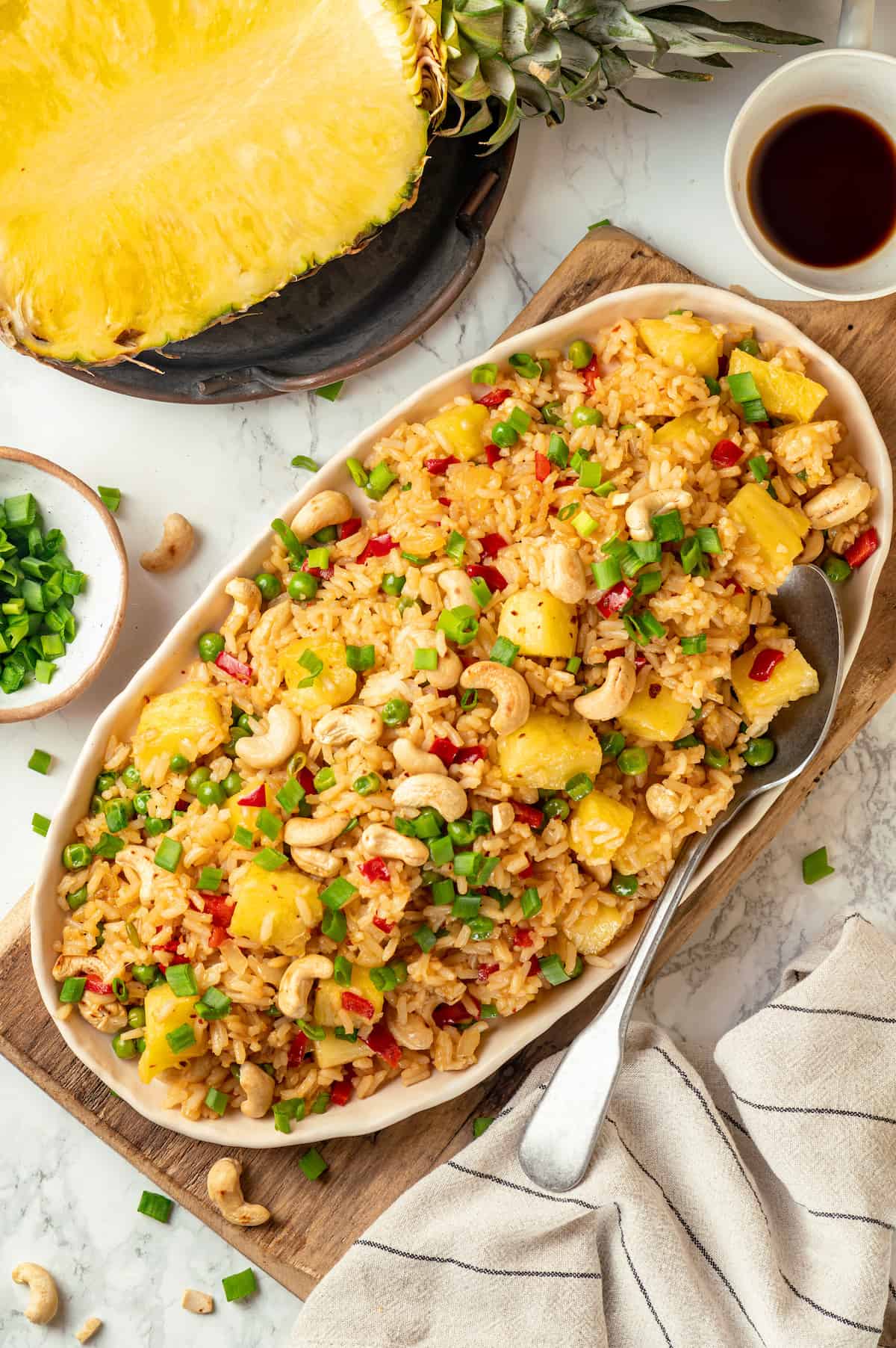 Overhead view of pineapple fried rice on platter with large spoon