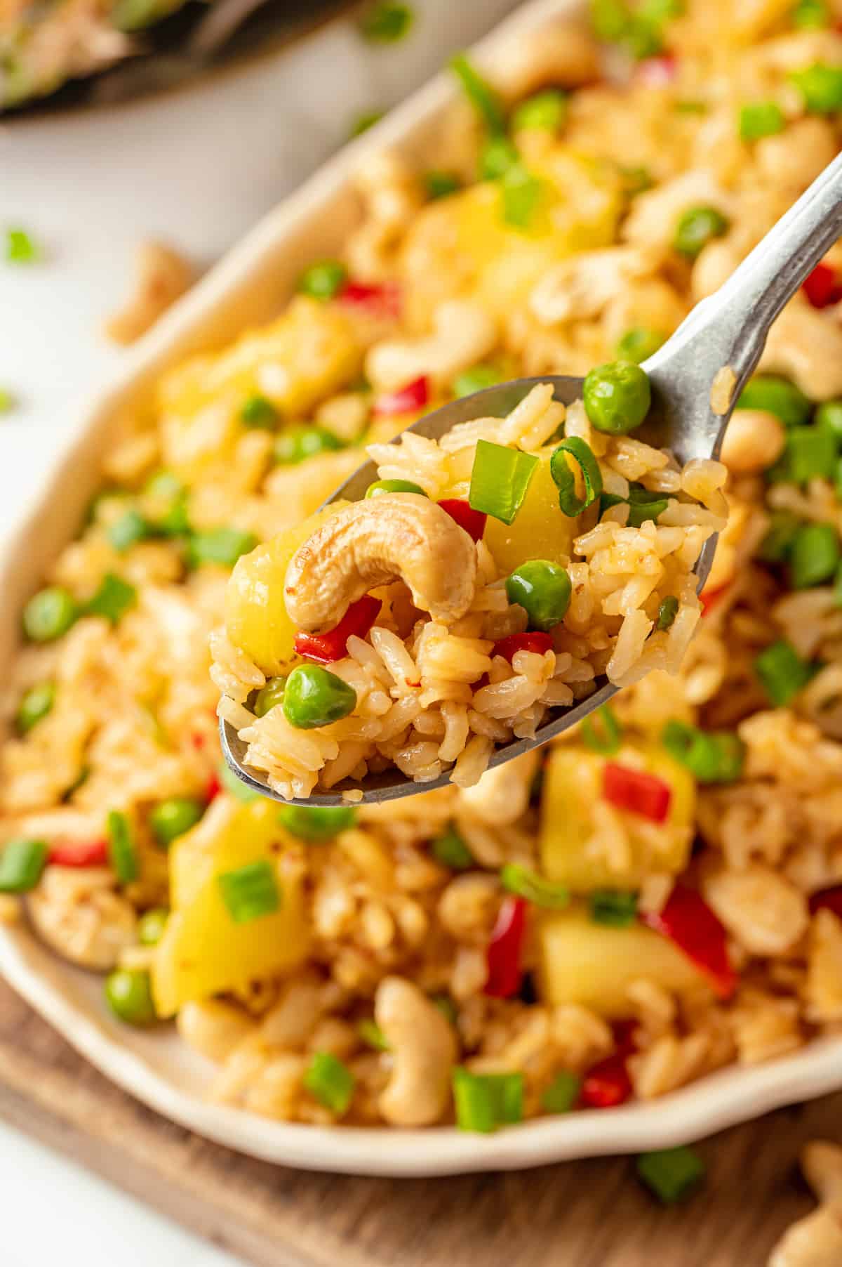 Spoonful of pineapple fried rice held over platter of rice