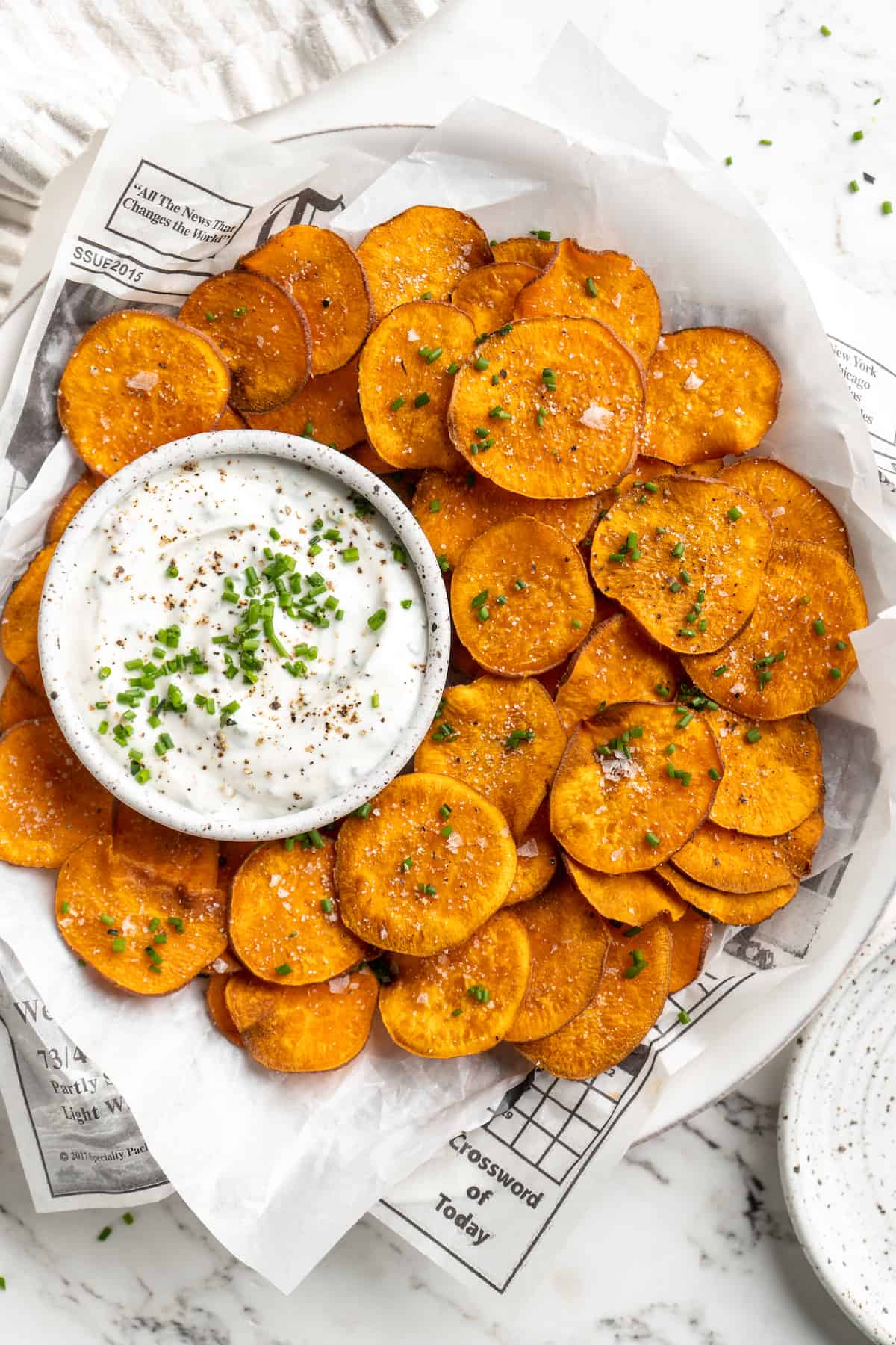Overhead view of sweet potato chips on plate with bowl of dip