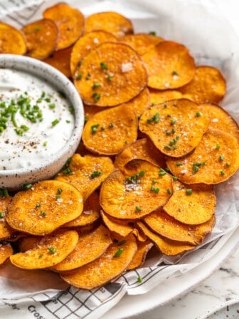 Baked sweet potato chips on plate with bowl of dip