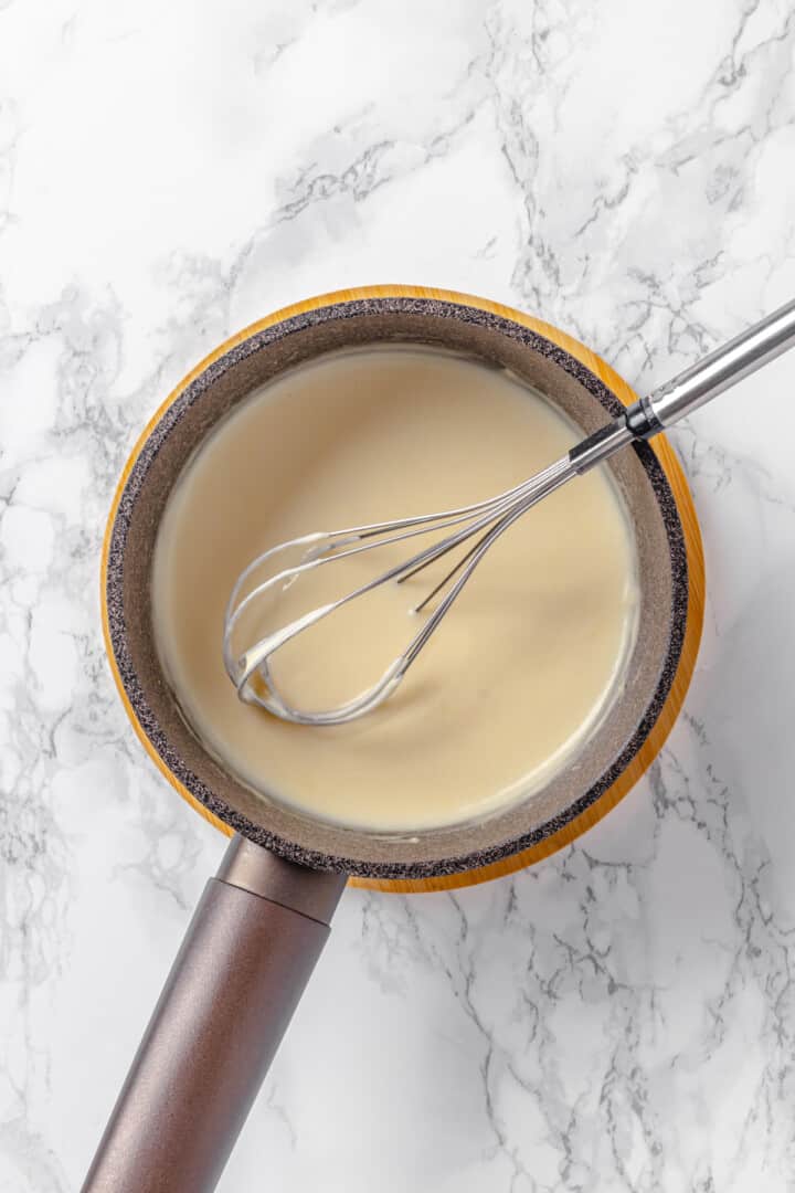 Overhead view of bechamel in saucepan with whisk