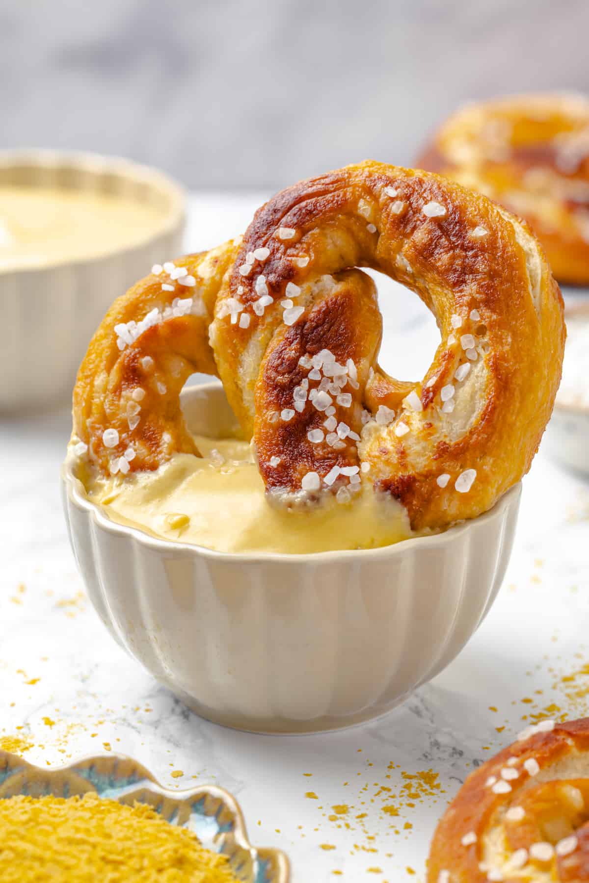 Soft pretzel being dipped into bowl of pretzel dip