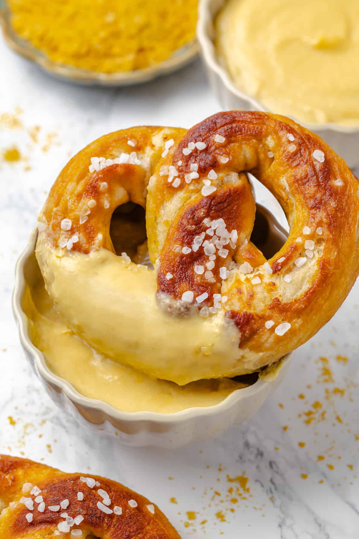 Soft pretzel dipped into bowl of cheesy pretzel dip